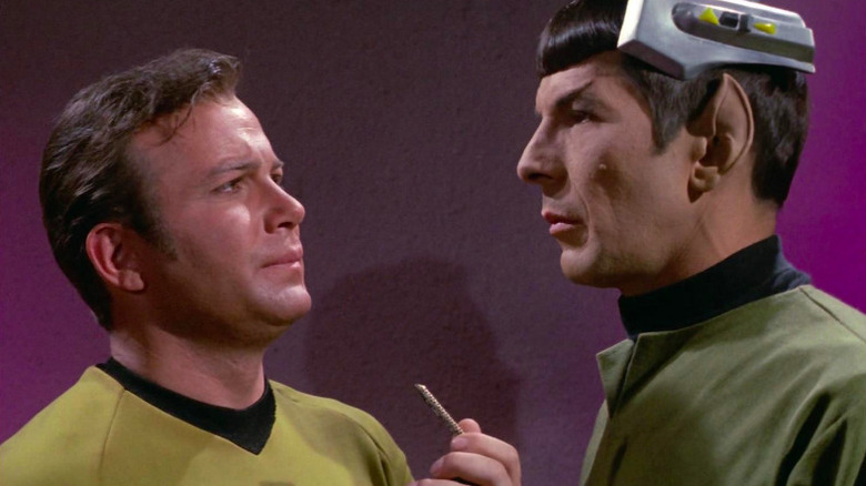 William Shatner as Captain Kirk holding handheld device and Leonard Nimoy as Spock with device on his head in Star Trek