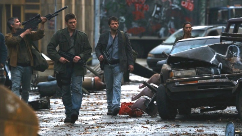 Jensen Ackles as Dean and Misha Collins as Castiel walking around post-apocalyptic street with guns in Supernatural
