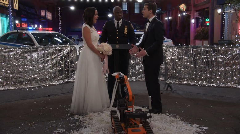 Captain Raymond Holt (Andre Braugher) officiates the wedding of Amy Santiago (Melissa Fumero) and Jake Peralta (Andy Samberg) in Brooklyn Nine-Nine