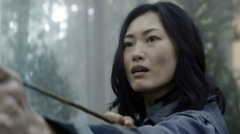 Anna Sawai as Cate holding an arrow in a forest in Monarch Legacy of Monsters