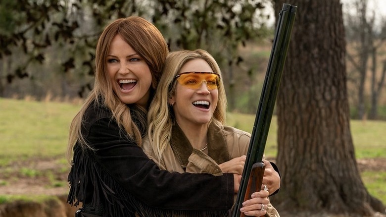 Malin Akerman as Margo hugging Brittany Snow as Sophie while holding a shotgun in The Hunting Wives