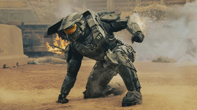 Master Chief in grey suit and helmet, crouching with fist on the ground