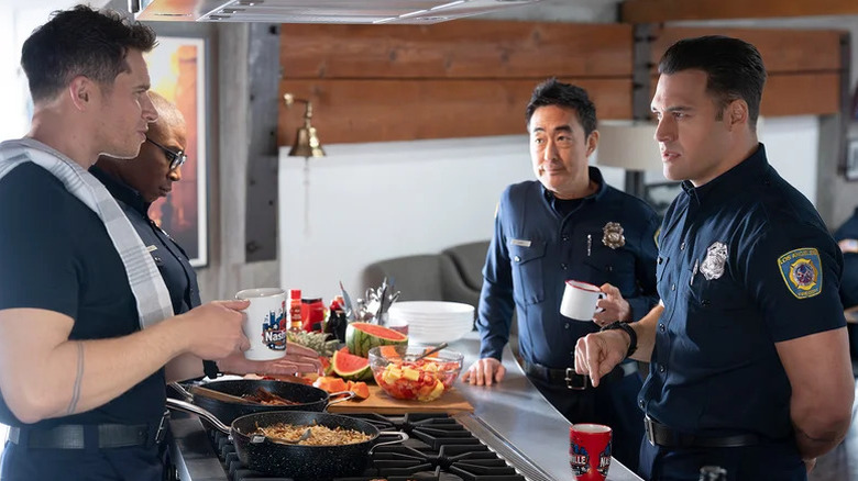 Aisha Hinds as Hen, Oliver Stark as Buck, Kenneth Choi as Chimney, and Ryan Guzman as Eddie standing around firehouse kitchen in "9-1-1."
