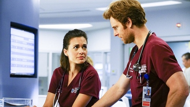 Torrey DeVitto as Natalie and Nick Gehlfuss as Will wearing red scrubs in "Chicago Med."