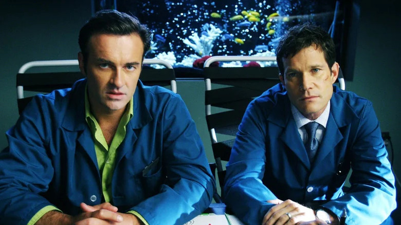 Julian McMahon as Christian and Dylan Walsh as Sean sitting in blue doctor's coats in front of fish tank in "Nip/Tuck."