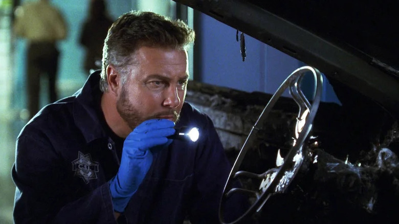 William Petersen's Gil Grissom shining a flashlight on a steering wheel on CSI: Crime Scene Investigation