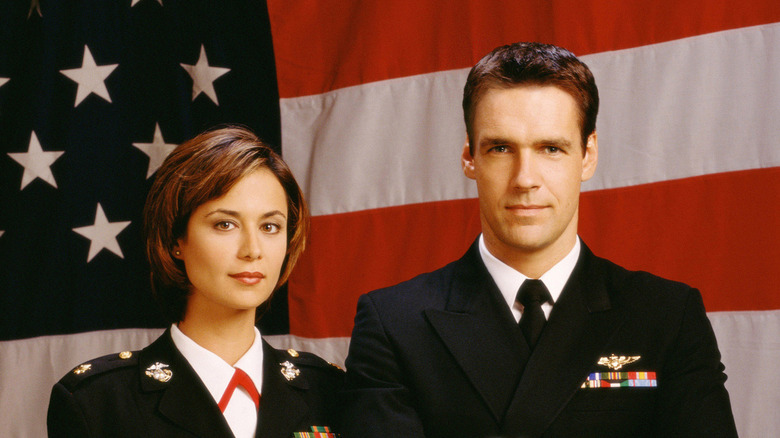 Catherine Bell's Sarah "Mac" McKenzie and David James Elliott's Harmon Rabb Jr. in front of the U.S. flag on JAG