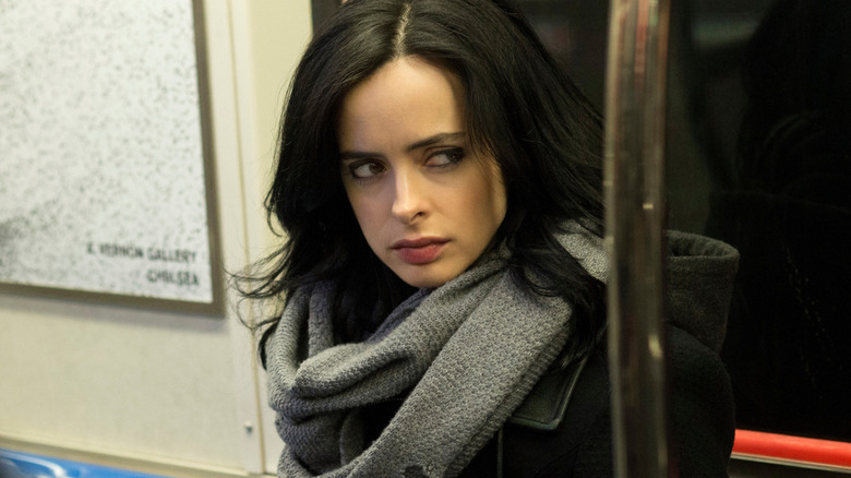 Jessica Jones eyes something suspiciously while seated in a subway car