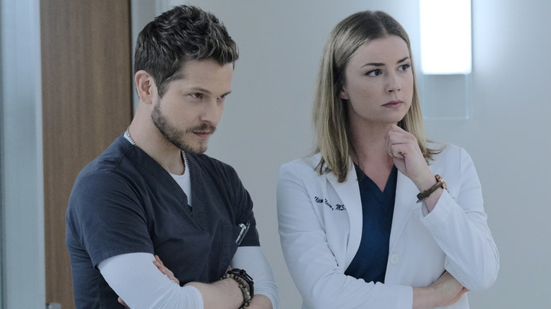 Dr. Conrad Hawkins and Nicolette Nevin in hospital scrubs, looking on