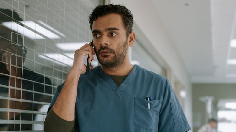 Dr. Bash Hamed holding cell phone in navy scrubs