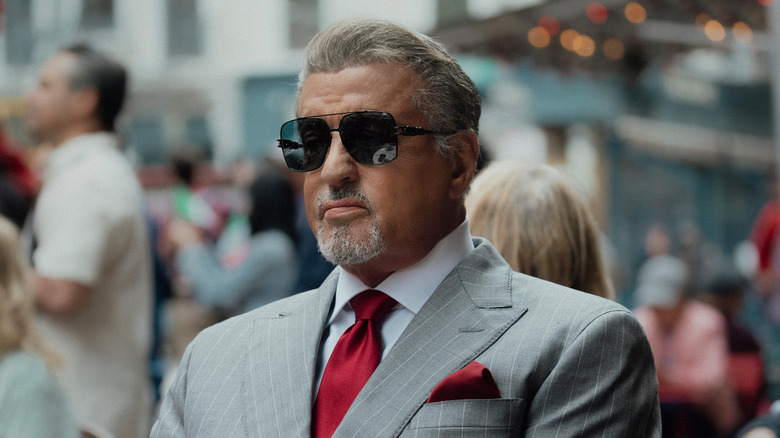 Sylvester Stallone as Dwight Manfredi, wearing shades and sitting in public in Tulsa King.