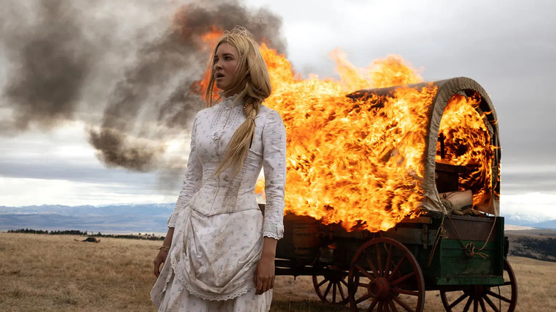 Isabel May as Elsa Dutton, standing in front of an on-fire wagon in 1883.