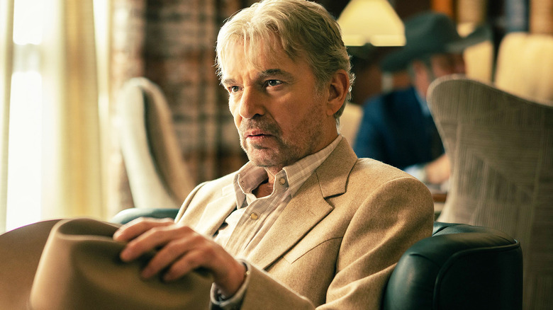 Billy Bob Thornton as Tommy Norris, sitting in a chair with his hat on his knee in Landman.