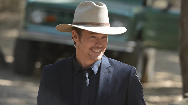 Timothy Olyphant as Raylan wearing a ten gallon hat and smiling in Justified