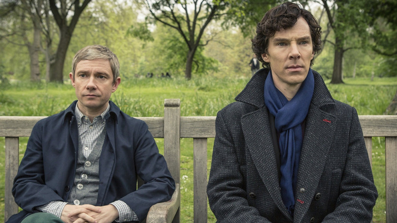 Martin Freeman and Benedict Cumberbatch as John Watson and Sherlock Holmes sitting on a park bench in Sherlock