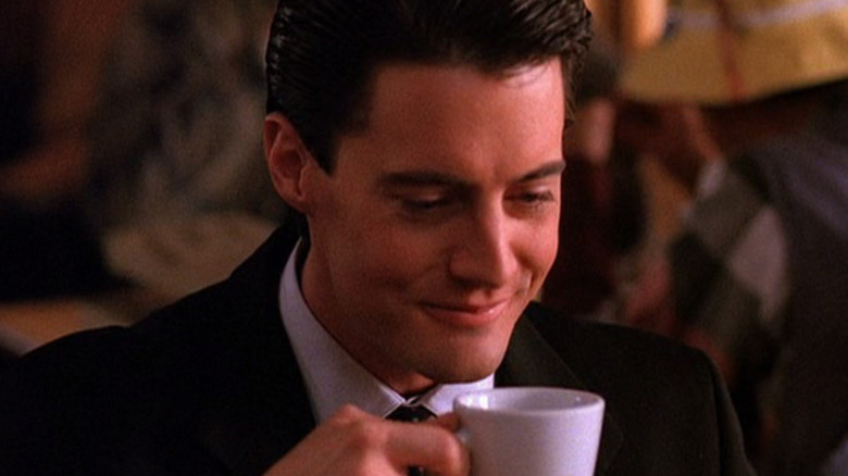 Kyle MacLachlan as Dale Cooper drinking coffee and smiling in Twin Peaks