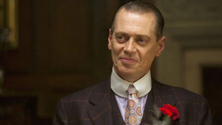 Steve Buscemi as Nucky smiling with suit and red flower pinned to his lapel in Boardwalk Empire