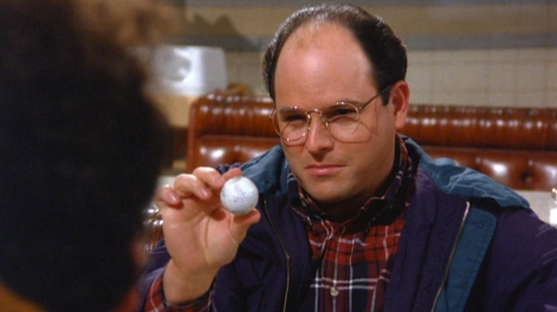 Jason Alexander as George Costanza holding a golf ball in Seinfeld.
