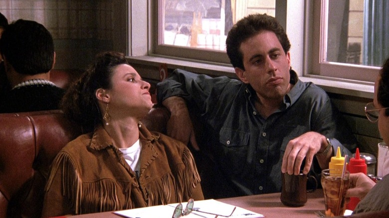 Julia Louis-Dreyfus as Elaine looking at Jerry Seinfeld as Jerry in a booth in Seinfeld.