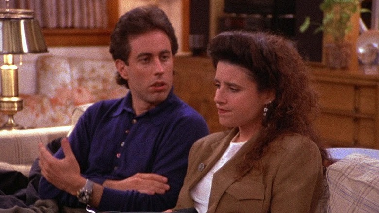 Jerry Seinfeld as Jerry Seinfeld looking at Julia Louis-Dreyfus as Elaine on a couch in Seinfeld.