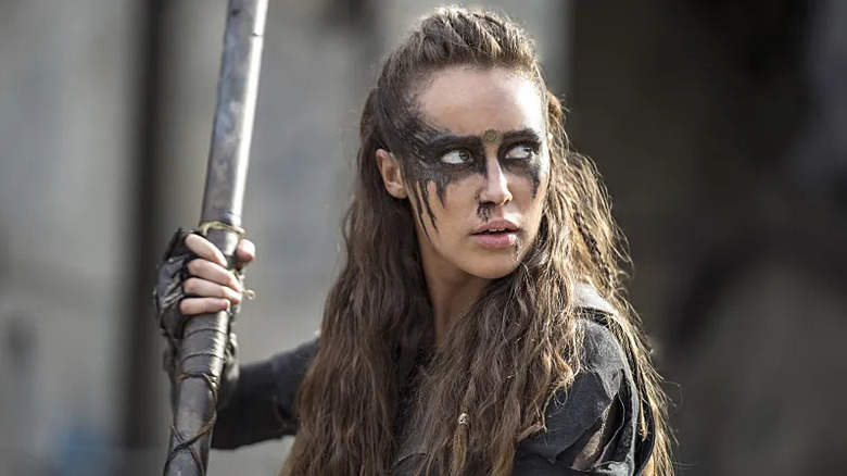 Lexa (Alycia Debnam-Carey) looks up wearing face paint and holding a spear in The 100