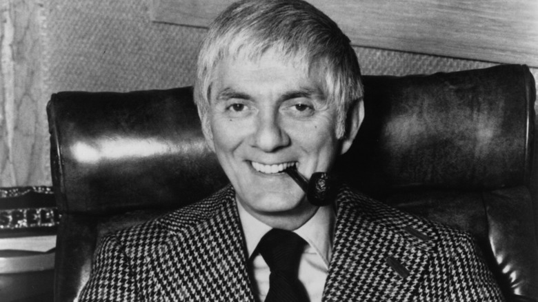 Executive producer Aaron Spelling seated behind desk and smiling