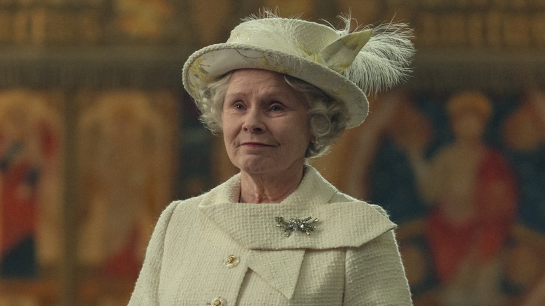 Queen Elizabeth smiling while wearing a pistachio green jacket and matching hat with feathers