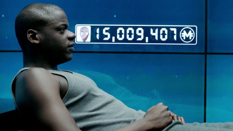 Bing lying next to the screen wall displaying his number of merits on Black Mirror S1E2