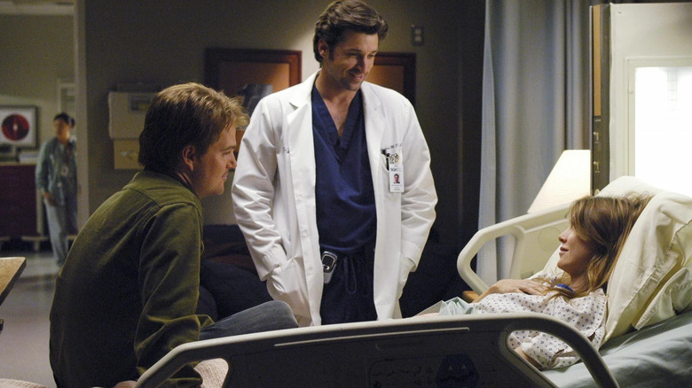 Finn (Chris O'Donnell) and Derek (Patrick Dempsey) by Meredith's (Ellen Pompeo) hospital bedside on Grey's Anatomy