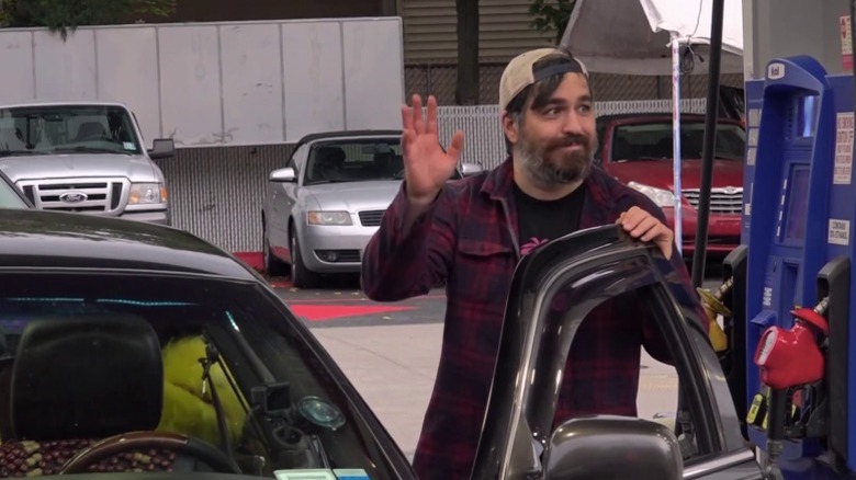 Q waving while filling up the car at a gas station on Impractical Jokers S9E3