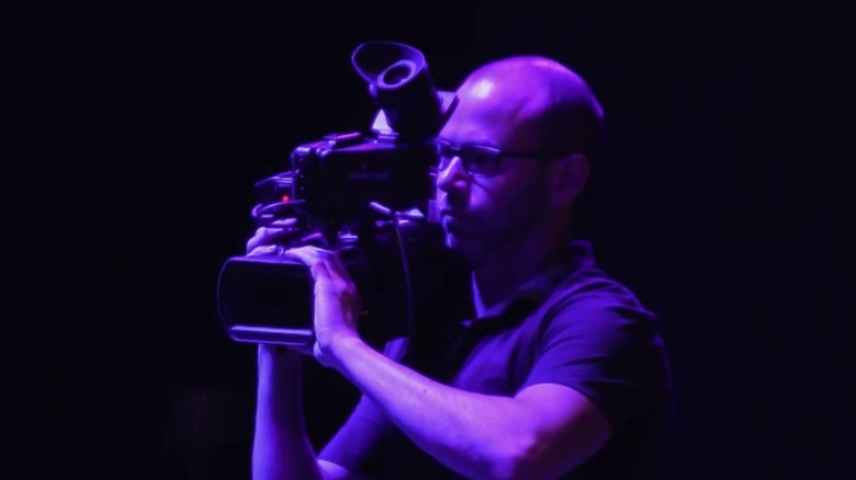 Murr operating a professional camera while bathed in purple light on Impractical Jokers S8E11