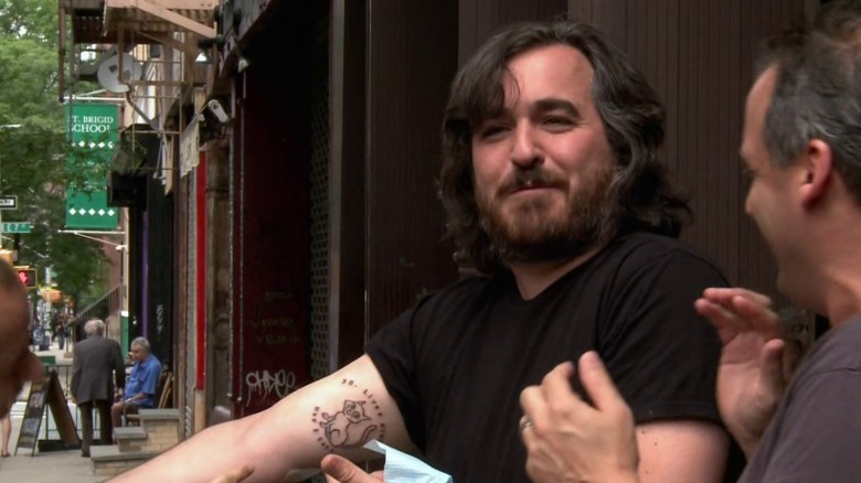 Q showing the drawing of a cat tattooed on his arm to the other Jokers on Impractical Jokers S3E27