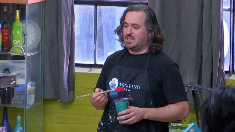 Q holding a paintbush and a plastic cup with paint on Impractical Jokers S6E7