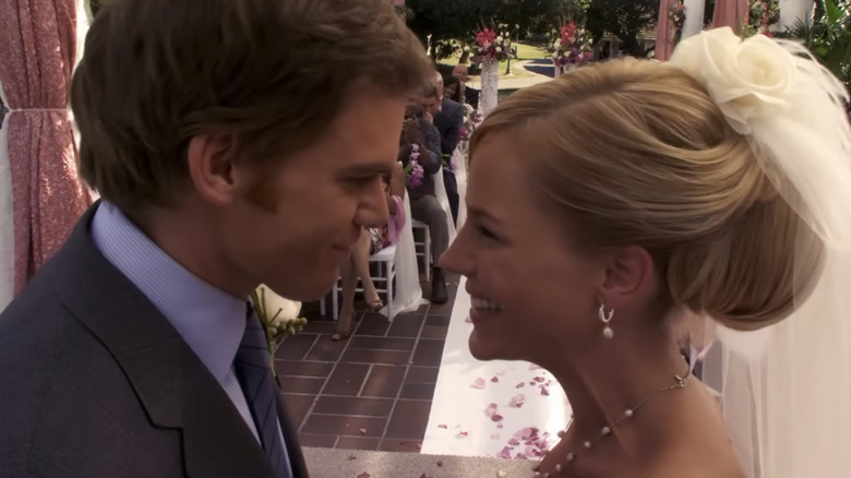 Michael C. Hall as Dexter with brown hair wearing a dark suit and Julie Benz as Rita Bennett with blond hair wearing a wedding dress and veil, looking at each other.