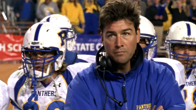 Coach Taylor standing on the sidelines during a football game on Friday Night Lights