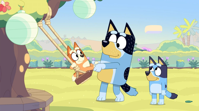 Bluey watching Bandit pull Bingo on a tree swing in Bluey