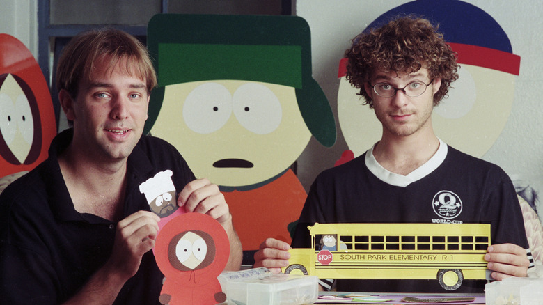 Matt Stone and Trey Parker holding paper cutouts in their office in 1997