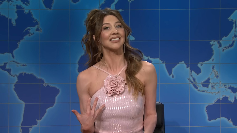 Heidi Gardner wearing a pink dress and talking on SNL