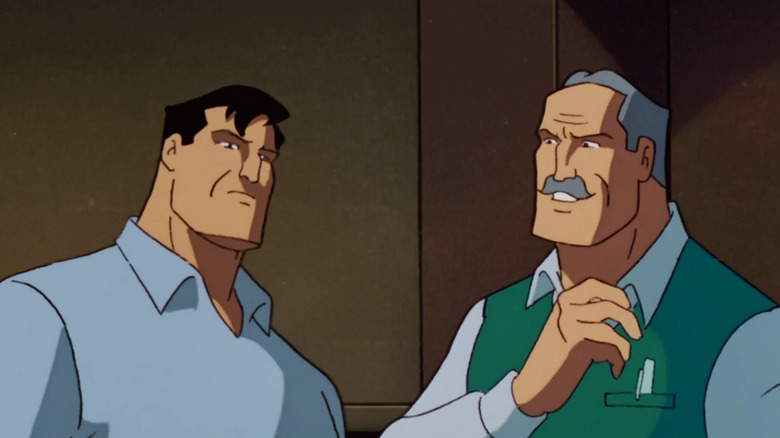Bruce Wayne and his father Thomas Wayne. On the left, the man has black hair and is wearing a blue open collar polo shirt. On the right, his father has receding gray hair and a mustache, he's wearing a white shirt and a green sleeveless sweater.