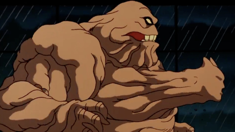 A side profile shot of Clayface, a large brown sludge man, with Batman's face emerging out of his chest.
