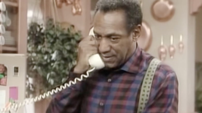 Dr. Cliff Huxtable on phone in kitchen scowling