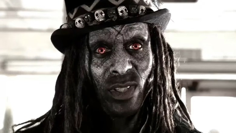 Papa Legba smirking while standing in a restaurant in "American Horror Story"