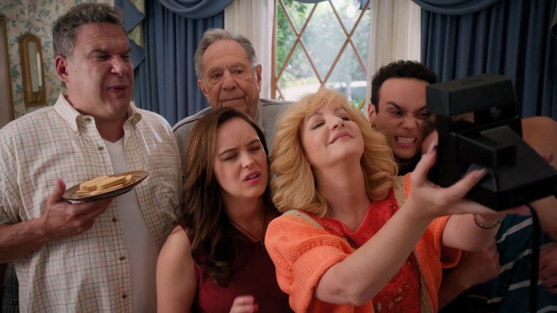 The cast of The Goldbergs on set, posing with a camera