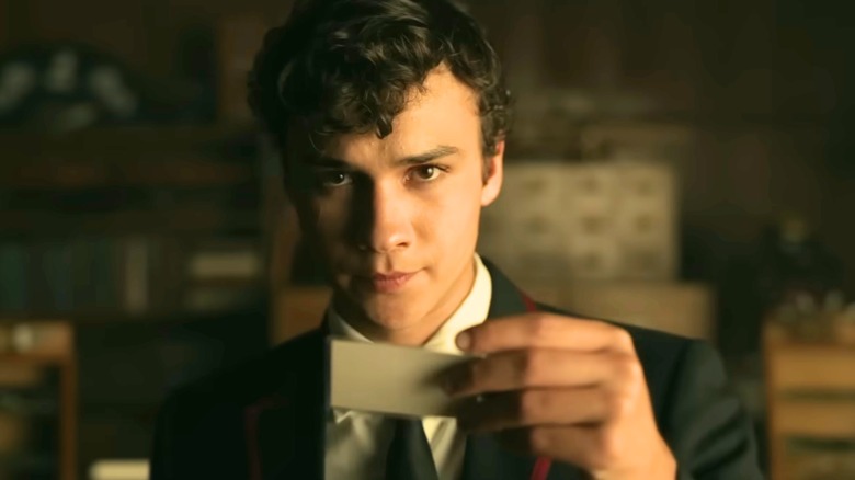 Marcus Lopez Arguello wearing school uniform and holding a card in his left hand in "Deadly Class."