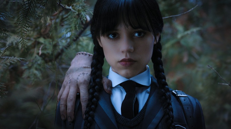 Wednesday Addams in school uniform with Thing on her soldier in "Wednesday."