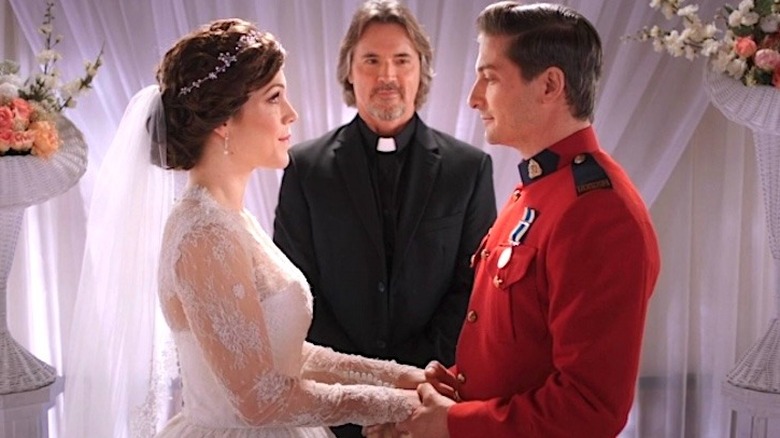 Elizabeth in a white wedding dress facing Jack in a red suit in front of a priest in black in When Calls the Heart