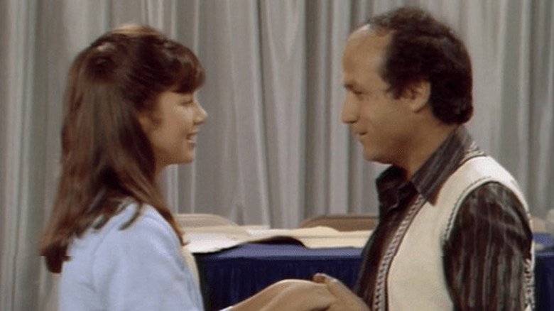 Mallory (Justine Bateman) smiles at her Uncle Arthur (David Spielberg), who holds her hands with a creepy smile with curtains in the background in Family Ties