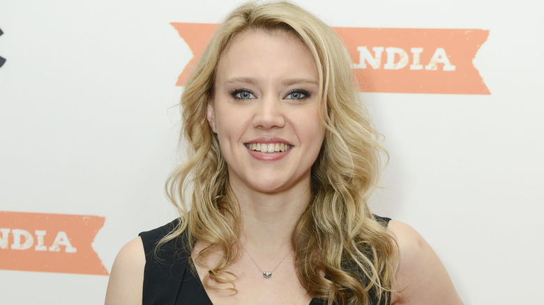 Kate McKinnon smiling and posing on a red carpet at an event