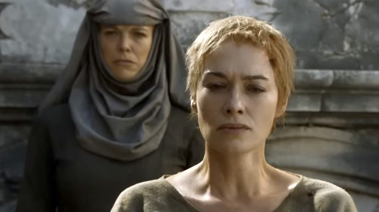 Hannah Waddingham in a gray habit-style outfit, standing behind a freshly shorn Cersei Lannister.