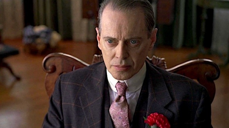 Nucky Thompson in a black suit sitting in a chair in Boardwalk Empire